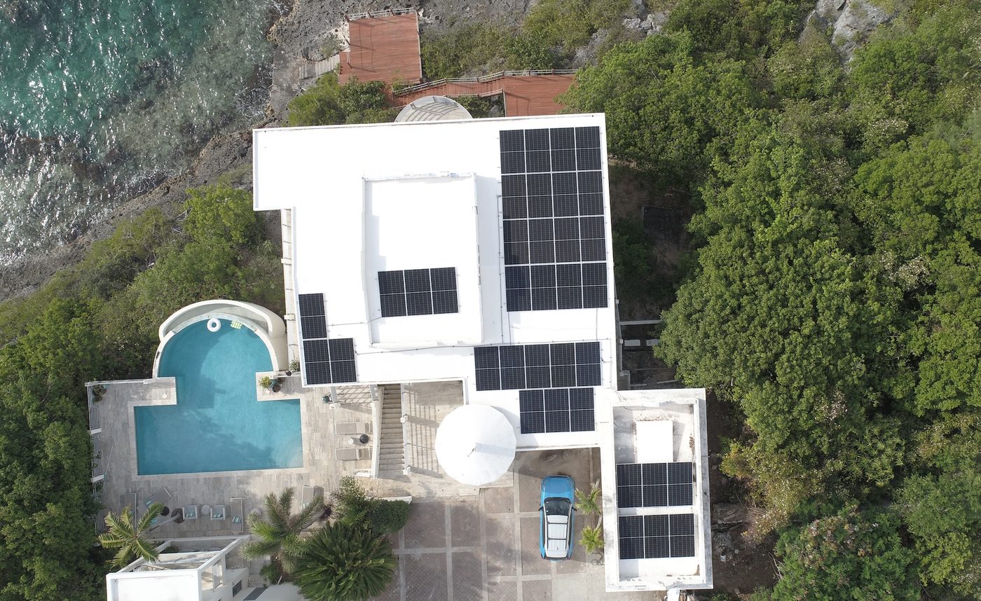 Drone top-down view of villa with full roof solar panel coverage